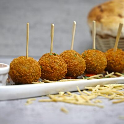 Tasty golden appetizer balls served with a spicy sauce, perfect for gatherings.