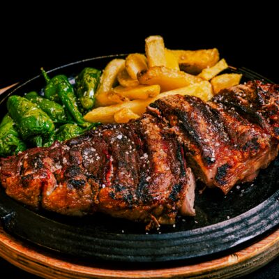 Delicious grilled steak served with fries and green peppers, a perfect dinner meal.
