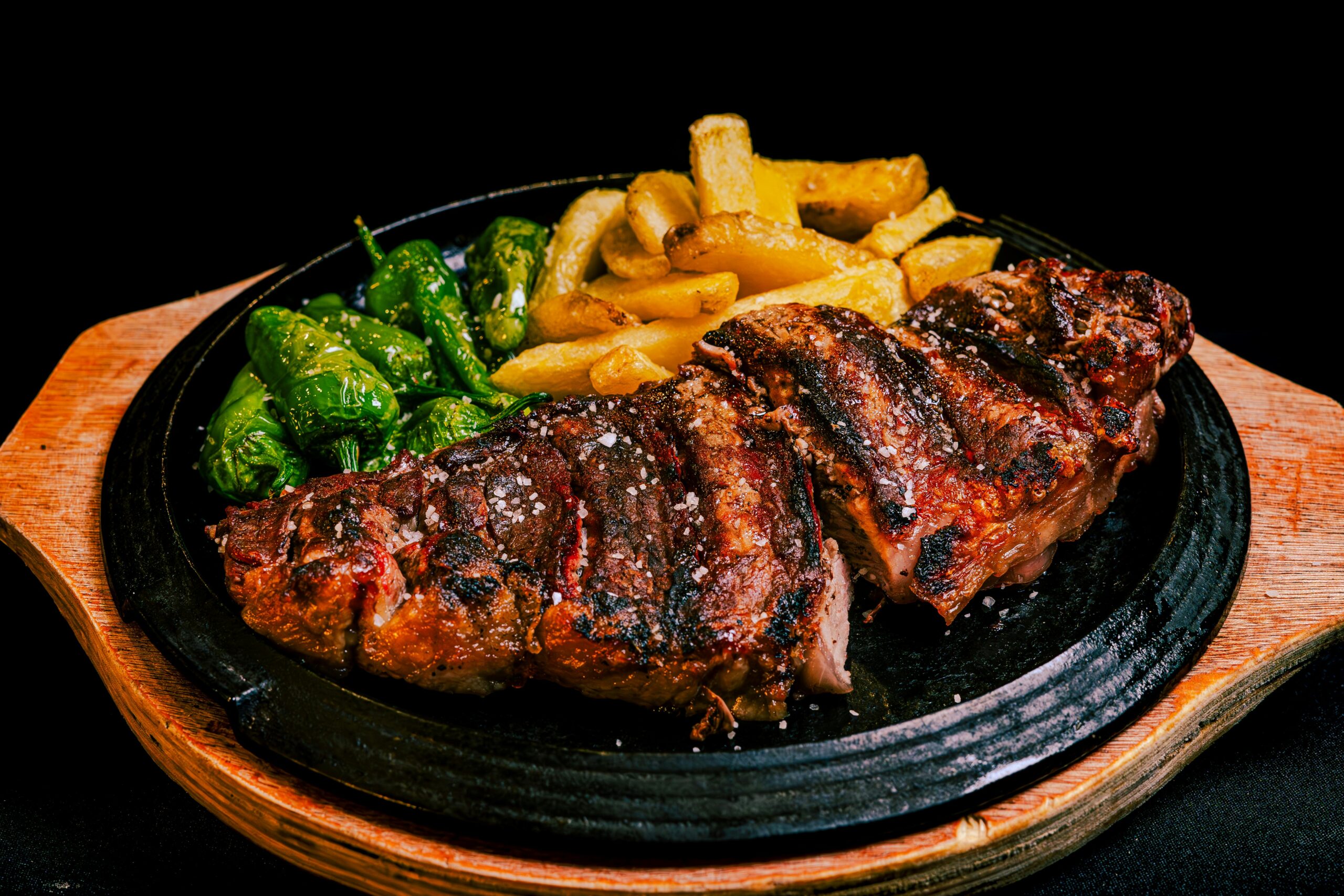 Delicious grilled steak served with fries and green peppers, a perfect dinner meal.