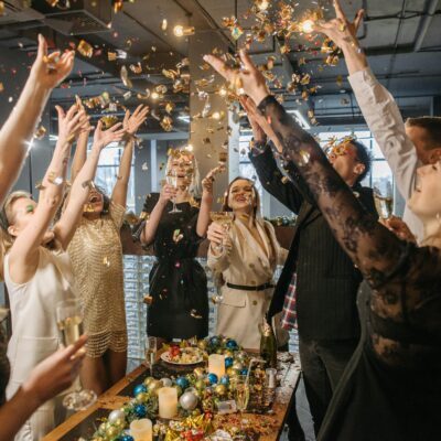 A lively gathering of adults celebrating indoors with confetti and champagne.