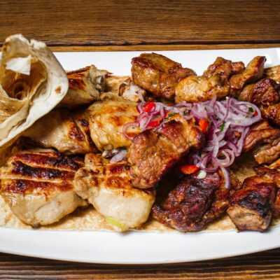 Exquisite grilled meat selection served with onions and flatbread on a wooden table.