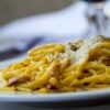 Close-up of spaghetti carbonara topped with grated Parmesan cheese on a plate, perfect for Italian cuisine lovers.