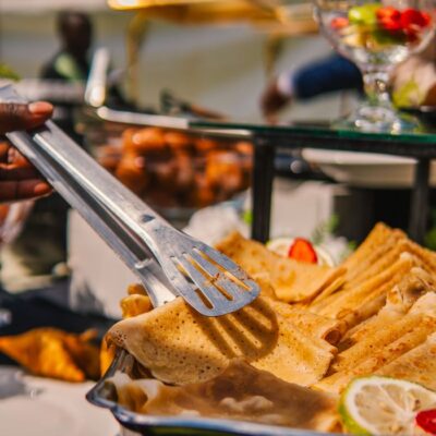 A vibrant outdoor buffet showcasing delicious crepes and fresh fruits in a sunny setting.
